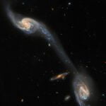 Hubble explores two galaxies connected by a glowing bridge
